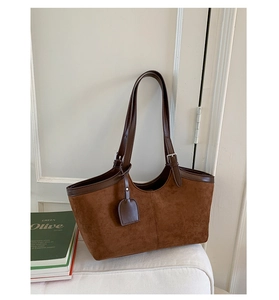 Detail of retro brown tote bag with adjustable leather handles and smooth metal buckle