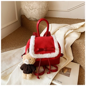 Detail of red drawstring backpack with white plush trim and teddy bear charm