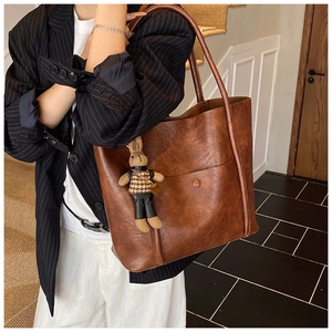 Detail of vintage brown tote bag with rabbit charm and decorative buckle pocket