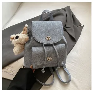 Dettaglio dello zaino azzurro con chiusura a scatto in argento e ciondolo a forma di orso