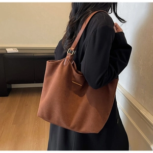 Detail van de bruine vintage tote tas in mat suède leer met gouden metalen accenten