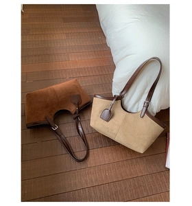 Detail view of large suede tote bags in deep brown and sand tan on wooden floor