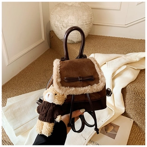 Detail of a brown suede mini backpack with faux fur trim, leather bow and bear charm