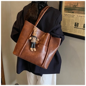 Brown vintage faux leather tote bag with cute bunny pendant shown on shoulder