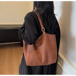 Detail van bruine matte shopper met slanke schouderbanden en gouden metalen gespen