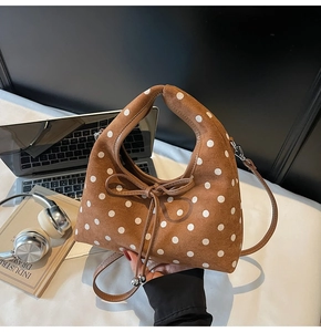 Gros plan d'un sac en daim marron à pois avec nœud et poignée circulaire intégrée
