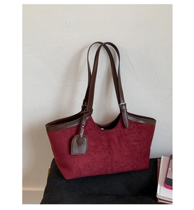 Detail view of burgundy faux suede tote bag with dark brown leather trimming and metal buckle