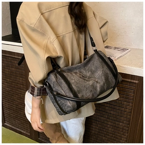 Close-up of vintage canvas cylinder crossbody bag with leather straps on a model