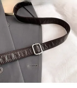 Close-up of adjustable strap with silver metal buckle on brown pebble leather tote bag