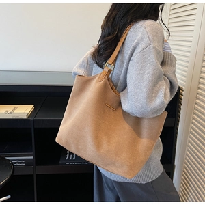 Detail van bruine suède shopper met gouden gesp en minimalistische metalen balk op de riem