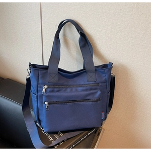 Détail d'un cabas en nylon bleu foncé avec poches zippées doubles et étiquette de marque