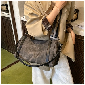 Detail view of large charcoal vintage crossbody bag worn by a model in a cozy indoor setting
