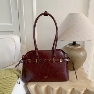 Détail d'un sac cabas en cuir ciré bordeaux montrant la boucle dorée et le logo