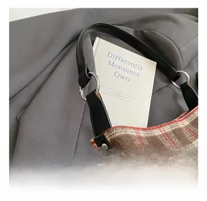 Detail of plaid shoulder bag with black leather trim and silver studs on suit background