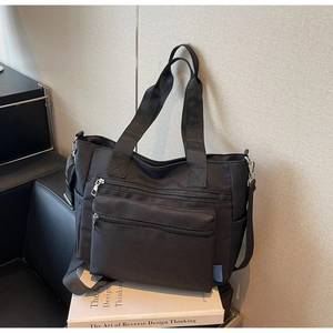 Détail du sac fourre-tout en nylon noir avec doubles poches zippées et bandoulière
