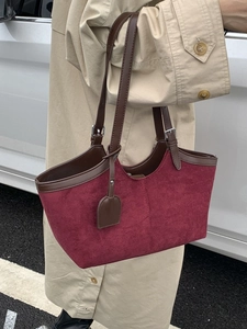 Chic burgundy suede tote bag with brown leather handles on a beige trench coat