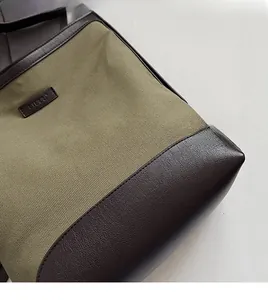 Detailed close-up of olive canvas and brown leather stitching on minimalist shoulder bag