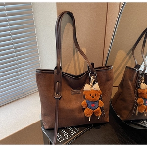 Detail view of dark brown faux suede tote bag featuring a cute bear keychain charm