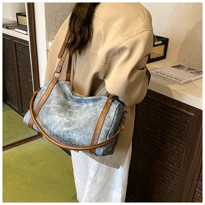 Detail view of retro denim shoulder bag with brown leather straps and silver hardware