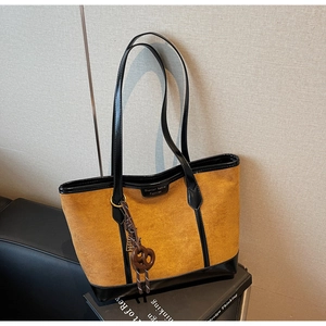 Dettaglio di una borsa tote grande in camoscio marrone con finiture in pelle nera