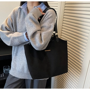 Detail van zwarte matte shopper tas met minimalistische gouden metalen accenten en textuur