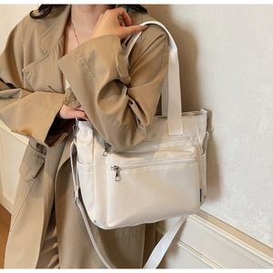 Gros plan sur un sac cabas en nylon blanc avec poches zippées et poignées tissées porté