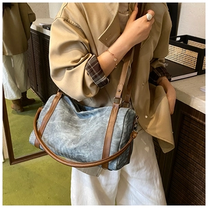 Detail of vintage cylindrical shoulder bag in distressed blue canvas and brown leather