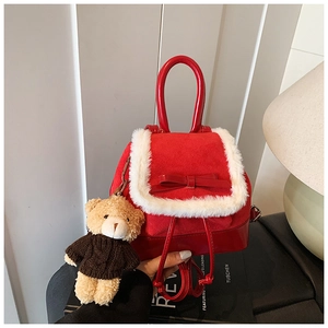 Close-up of red suede backpack with plush trim, bow detail and teddy bear charm