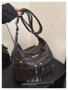 Detail view of coffee brown soft leather tote bag with multiple zip pockets and adjustable strap