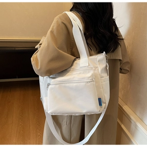 Vue latérale du grand sac bandoulière en nylon blanc avec plusieurs poches zippées