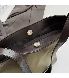 Detail of the magnetic buckle closure on a woven canvas tote bag with leather trim