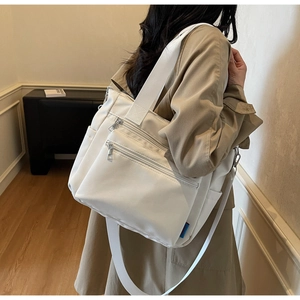 Vue détaillée du grand sac cabas blanc en nylon montrant les zips frontaux et poches de côté