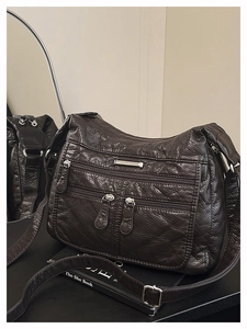 Detail of soft wrinkled leather bag with multi-zipper pockets and silver hardware