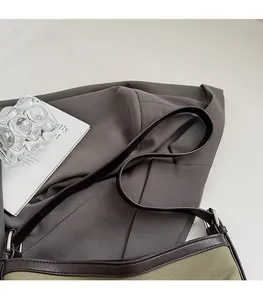 Detail of adjustable leather strap and silver buckle on khaki canvas shoulder bag