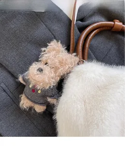 Nahaufnahme eines Plüsch-Hundeanhängers mit grauem Pullover an einer flauschigen Tasche
