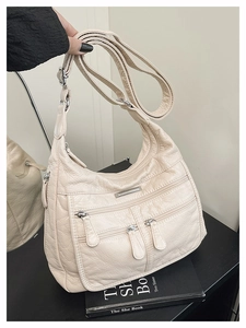 Detail view of cream soft leather tote bag with three front zippers and silver hardware