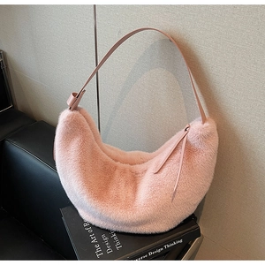 Detail of pink faux fur crescent bag with leather strap on black leather sofa