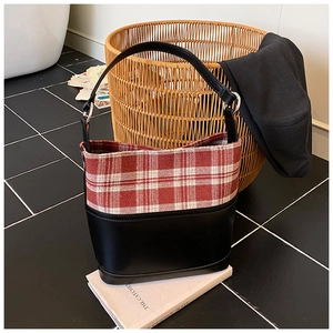 Detail of red and white tweed bucket bag on white books in a stylish setting