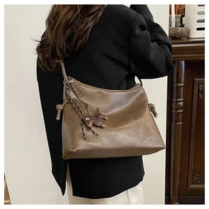 Detail view of retro brown shoulder bag with decorative knots and animal charm pendant