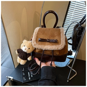 Detail of suede backpack with plush trim, patent leather bow and a cute bear charm