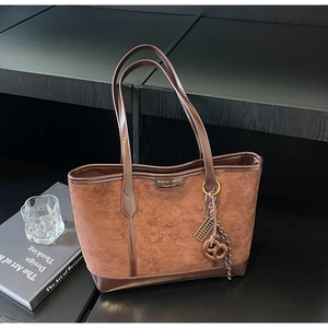 Dettaglio macro di borsa tote marrone scuro con trama scamosciata e finiture lucide