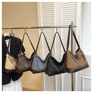 Five assorted canvas and leather hobo shoulder bags hanging on a rack in multiple colors