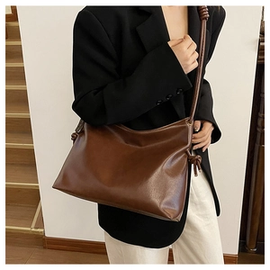 Detail of vintage brown leather bucket bag with decorative knot and large capacity