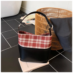 Detail of red and white plaid tweed and black leather bucket bag with silver buckle