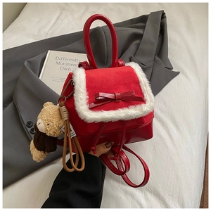 Detail of red suede backpack with fur trim, ribbon bow and cute plush bear charm