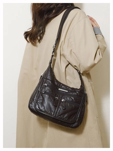 Detail of dark brown soft leather tote bag with pleat textures and dual zipper pockets