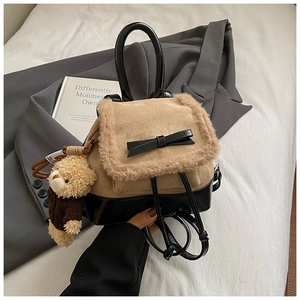 Detail of khaki plush backpack featuring black leather bow and cute bear charm pendant