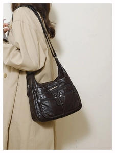 Detail of soft dark brown leather tote bag showing multiple zipper pockets and texture