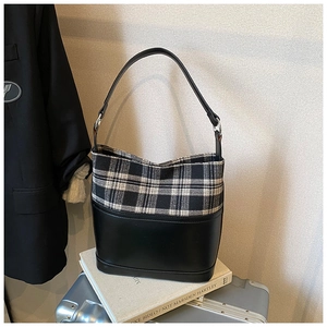 Detail of a chic bucket bag showing black and white plaid fabric and matte leather texture
