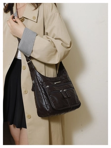 Detail view of brown soft leather tote bag with multiple zippers worn by model